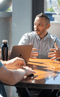 Professional sharing ideas during a daylight team meeting at a wooden conference table.